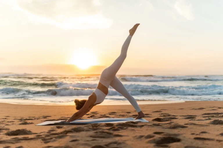 Woman doing yoga on the beach at sunset